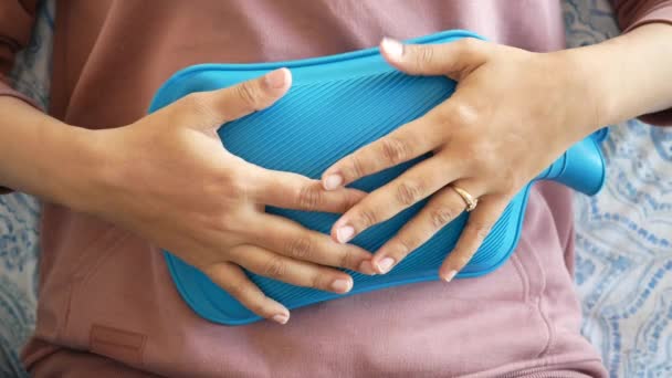mujer usando bolsa de agua caliente para el dolor de período - Metraje, vídeo