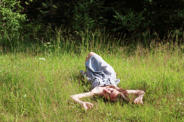 Beautiful girl in dress lying on meadow in woods and looking at  - Фото, изображение