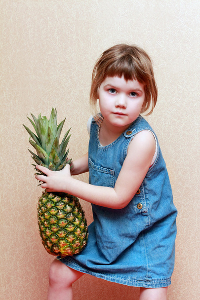 Girl in jeans dress holds big green pineapple - Photo, Image