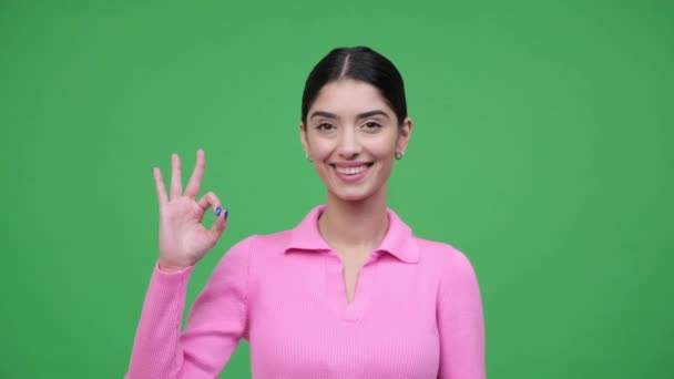 Selbstbewusstes und freundliches kaukasisches Frauenporträt, das eine Handbewegung mit breitem Lächeln auf grünem Hintergrund zeigt. Genehmigung und Vertragsunterzeichnung. - Filmmaterial, Video