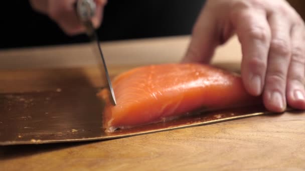 Tagliare il salmone a pezzi con un coltello. Cucinare piatti di pesce rosso. Rallentatore. - Filmati, video