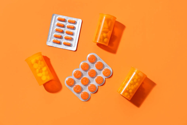 Таблетки и таблетки в блистерных упаковках на оранжевом фоне - Фото, изображение
