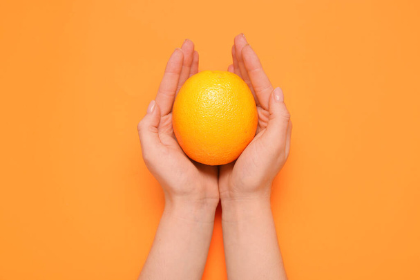 Naisten kädet tilalla tuoretta oranssi väri tausta - Valokuva, kuva