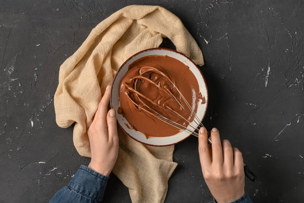 Kobieta przygotowuje smaczne stopione czekolady na czarnym tle - Zdjęcie, obraz
