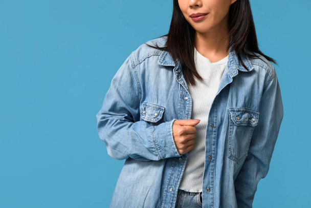 Belle jeune femme asiatique en jean élégant sur fond bleu, gros plan - Photo, image