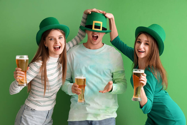 Jongeren met bier op groene achtergrond. St. Patrick 's Day viering - Foto, afbeelding