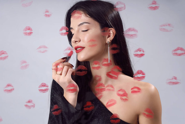 Mujer joven con lápiz labial y marcas de beso sobre fondo claro, primer plano - Foto, imagen