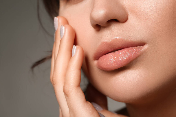 Young woman with beautiful lips and stylish manicure on grey background, closeup - Photo, Image