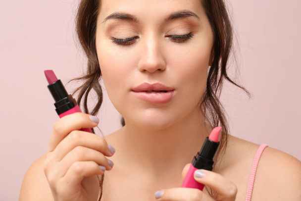 Young woman with lipsticks on color background, closeup - Photo, Image
