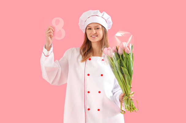 Joven chef femenina con ramo de tulipanes y figura de papel 8 sobre fondo rosa. Celebración del Día Internacional de la Mujer - Foto, Imagen