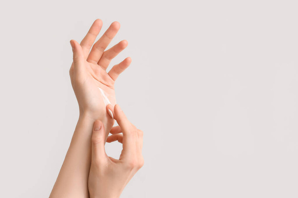 Woman applying cream onto her hands against light background, closeup - Photo, Image