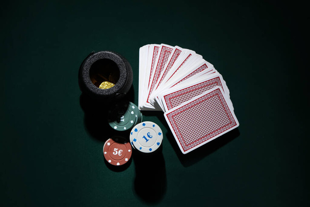 Pokerchips, Pot mit Münzen und Karten auf dunkelgrünem Hintergrund. St. Patrick 's Day Feier - Foto, Bild