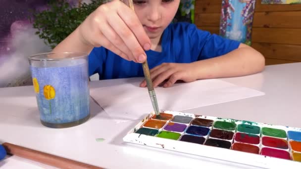 Genç sanatsal ifade, çocukluk hobisi. Tatlı küçük bir çocuk suluboya resim yapar, yaratıcılığını ve hayal gücünü garip çizimler ve kapalı alan bitkileriyle keşfeder. - Video, Çekim