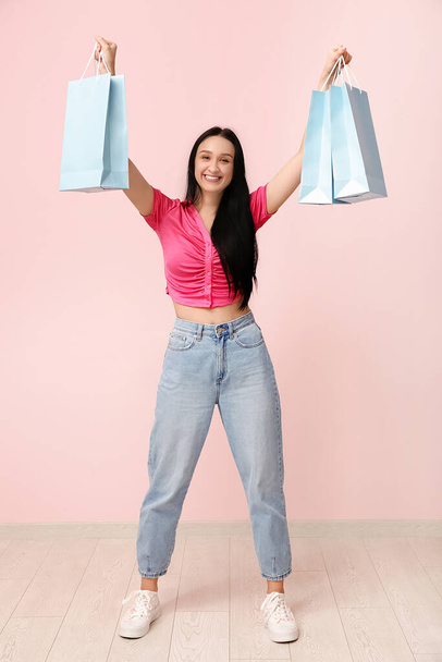 Krásná mladá žena s nákupními taškami u růžové zdi. Mezinárodní den žen - Fotografie, Obrázek