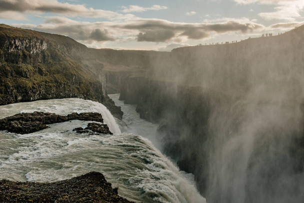 una cascata con una persona in piedi sul bordo - Foto, immagini