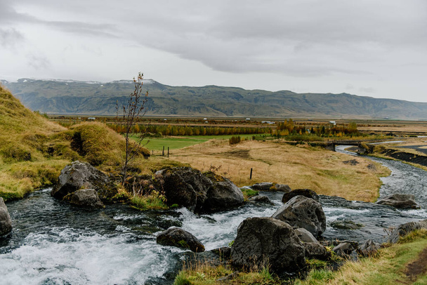 річка, що проходить через пишний зелений схил пагорба - Фото, зображення