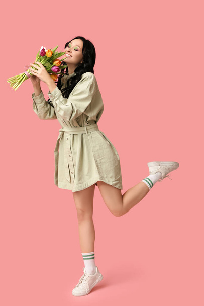 ピンクの背景にチューリップの花束を持つ幸せな若い女性. 国際女性デー - 写真・画像