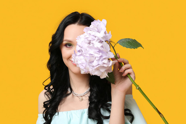 Krásná mladá žena s hortenzie květiny na žlutém pozadí. Mezinárodní den žen - Fotografie, Obrázek