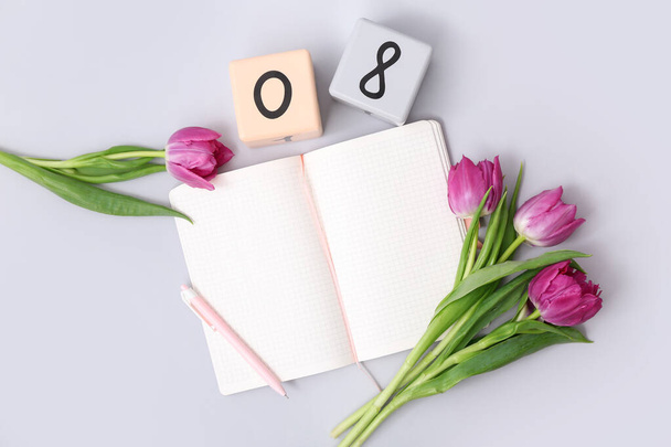 Kalendarz kostki z datą 08, piękne fioletowe tulipany i notatnik na szarym tle. Międzynarodowy Dzień Kobiet - Zdjęcie, obraz