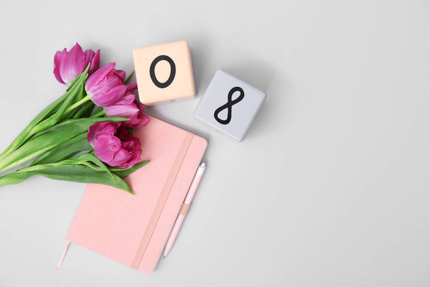 Kalendarz kostki z datą 08, piękne fioletowe tulipany i notatnik na szarym tle. Międzynarodowy Dzień Kobiet - Zdjęcie, obraz