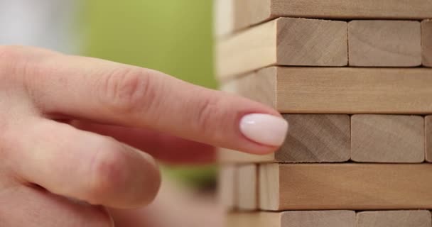 Woman hand closeup takes one block on tower of wooden blocks. Financial investment risks - Footage, Video
