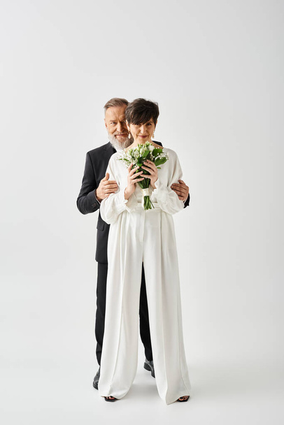 Жених и невеста средних лет в свадебных платьях отмечают свой особенный день вместе в студии. - Фото, изображение