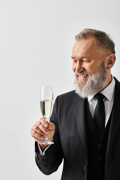 Ženich středního věku v elegantním obleku pozvedne sklenici šampaňského na oslavu svého svatebního dne. - Fotografie, Obrázek