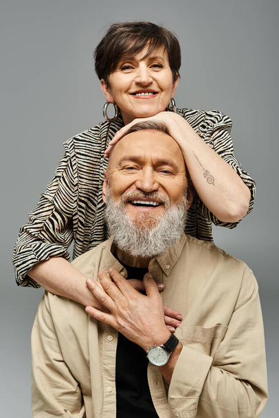 Ein Mann mittleren Alters stützt eine Frau auf seinen Schultern und zeigt Stärke und Vertrauen in einem stilvollen Studio-Ambiente. - Foto, Bild