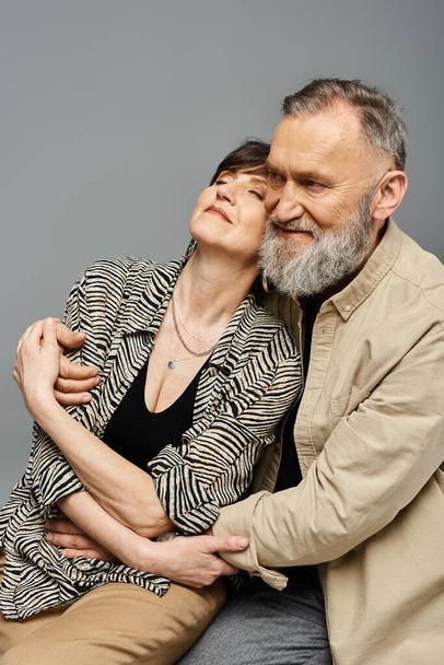 Пара середнього віку в стильному вбранні сидить близько один до одного, виключаючи витонченість і зв'язок. - Фото, зображення