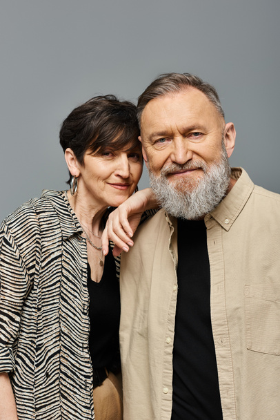 Een man en vrouw van middelbare leeftijd in stijlvolle kledij poseren sierlijk voor een portret in een atelieromgeving. - Foto, afbeelding