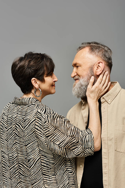 Ein Mann mittleren Alters und eine Frau in stilvoller Kleidung stehen anmutig Seite an Seite in einem Studio-Setting. - Foto, Bild