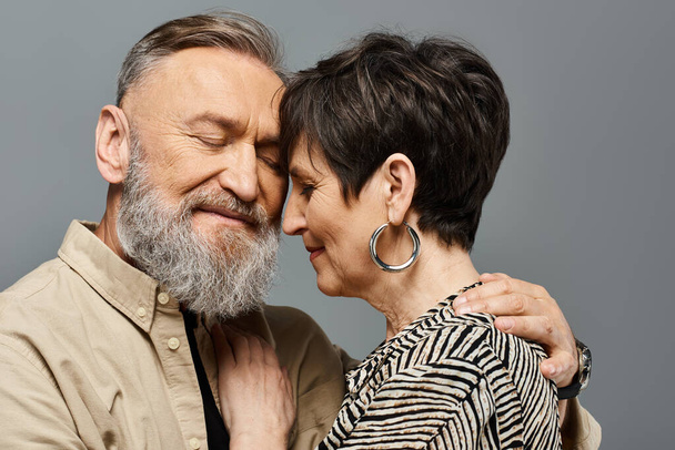 Mężczyzna i kobieta w średnim wieku, ubrani w stylowe stroje, czule przytulają się w studio, okazując miłość i więź. - Zdjęcie, obraz