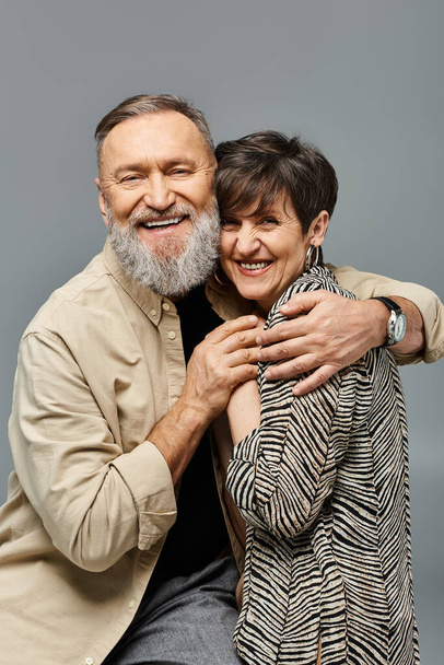 Ein Mann mittleren Alters und eine Frau in stilvoller Kleidung umarmen sich innig in einem Studio-Ambiente und strahlen Liebe und Verbundenheit aus. - Foto, Bild