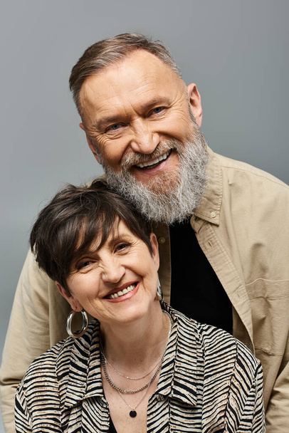 Un homme et une femme d'âge moyen en tenue à la mode posant affectueusement pour une caméra dans un décor de studio. - Photo, image