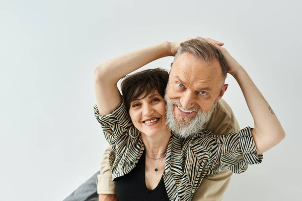 A middle-aged man and woman, stylishly dressed, strike a pose together in a studio setting. - Photo, Image