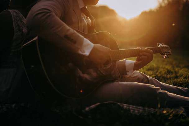 człowiek siedzący w trawie grający na gitarze - Zdjęcie, obraz