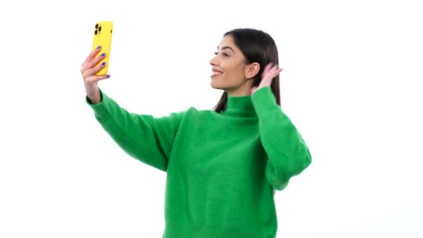 Innoissaan valkoihoinen nainen käyttää älypuhelinta puhumiseen videopuhelu, tervehdys vilkuttamalla käsi, nauraa valkoisella taustalla. Online-keskustelu sosiaalisessa mediassa. - Materiaali, video