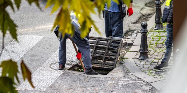 Groep onherkenbare werknemers repareert straat, voert taken uit om de weg- en riolering te onderhouden en te verbeteren. - Foto, afbeelding