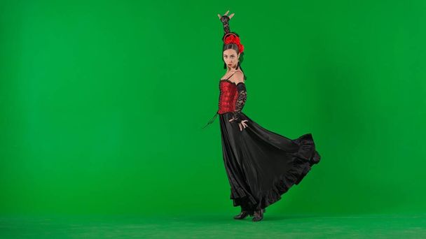 Modern choreography an dance. Woman dancer dancing on chroma key green screen. Female in flamenco style dress performs elegant spanish dance moves with her hands and body in the studio. - Zdjęcie, obraz