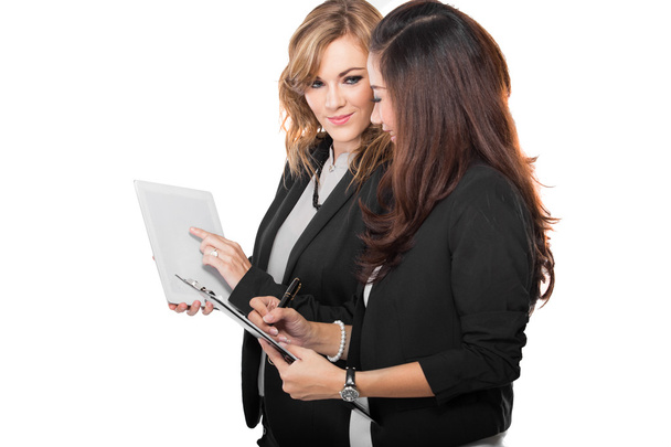 Two young businesswoman discuss with a clipboard, isolated - Foto, Imagem