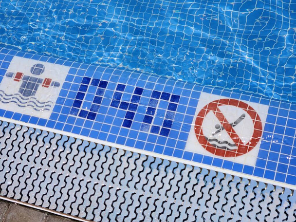 Näkymä altaan reunaan määritetyllä syvyydellä turvalliseen uintiin ja varoitusmerkki, joka kieltää sukeltamisen. Espanja. - Valokuva, kuva