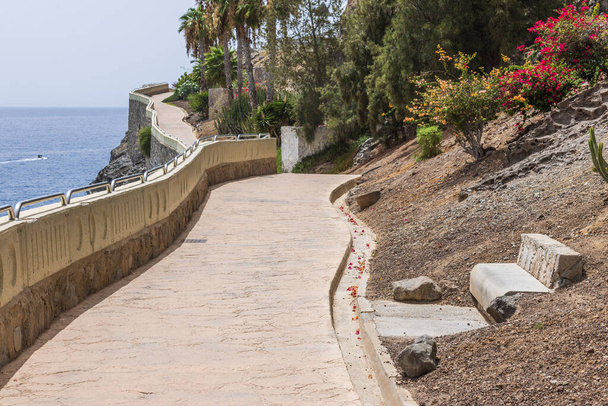 Beautiful view of a pedestrian pathway with a railing leading down to the seaside at the edge of a mountainous landscape. Spain. - Photo, Image
