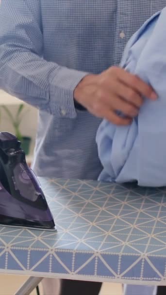 man ironing clothes in ironing board on background - Footage, Video