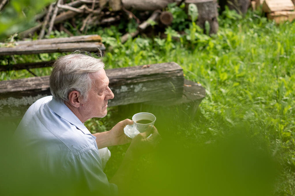 Літній чоловік сіє чай, з акцентом на релаксацію і простоту насолоди природою, ідеально підходить для відпочинку і виходу на пенсію, старших страхових концепцій. Високоякісна фотографія - Фото, зображення