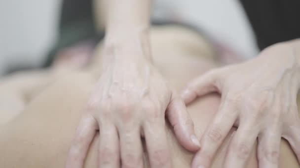 Die geschickten Hände des Masseurs sorgen für eine tiefe Gewebemassage am Bein des Klienten und lindern Muskelverspannungen in einer ruhigen Wellness-Umgebung.. - Filmmaterial, Video