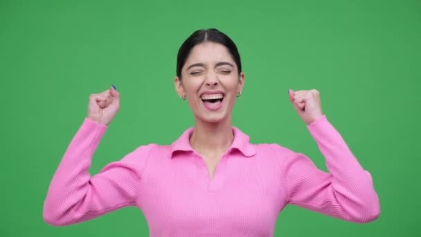 Jonge blanke vrouw portret, maken vuist pomp gebaar met brede glimlach, roepen ja, verheugen succes, prestatie op groene achtergrond. - Video