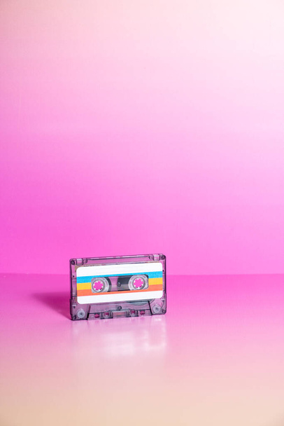Transparent audio cassette with labels on fuchsia background. - Photo, Image