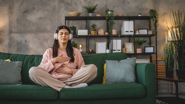 Одна женщина взрослая кавказская женщина тысячелетия с помощью наушников для онлайн-медитации практикуя внимательность йоги с закрытыми глазами дома реальные люди концепции самопомощи скопировать пространство - Фото, изображение