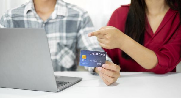 E-ticaret kavramı. Kredi kartı tutan mutlu çift online alışveriş yaparken ve dizüstü bilgisayar kullanırken kart numaralarını internet mağazasından satın almak ve ödemek için başvuruda bulunuyor.. - Fotoğraf, Görsel