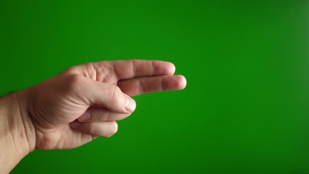 Un homme montre des ciseaux avec ses doigts sur un fond vert. Mouvement lent. - Séquence, vidéo